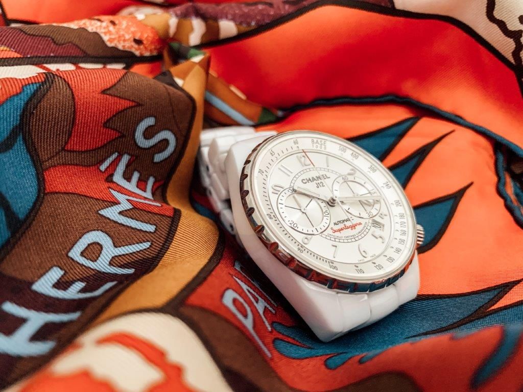 Fotografia de um lenço Hermès e de um relógio Chanel